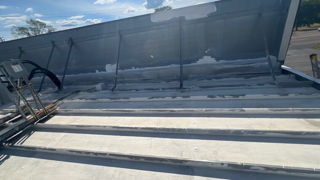 Low-slope commercial roof with mechanical equipment and aged coating details at a Liverpool fuel site.
